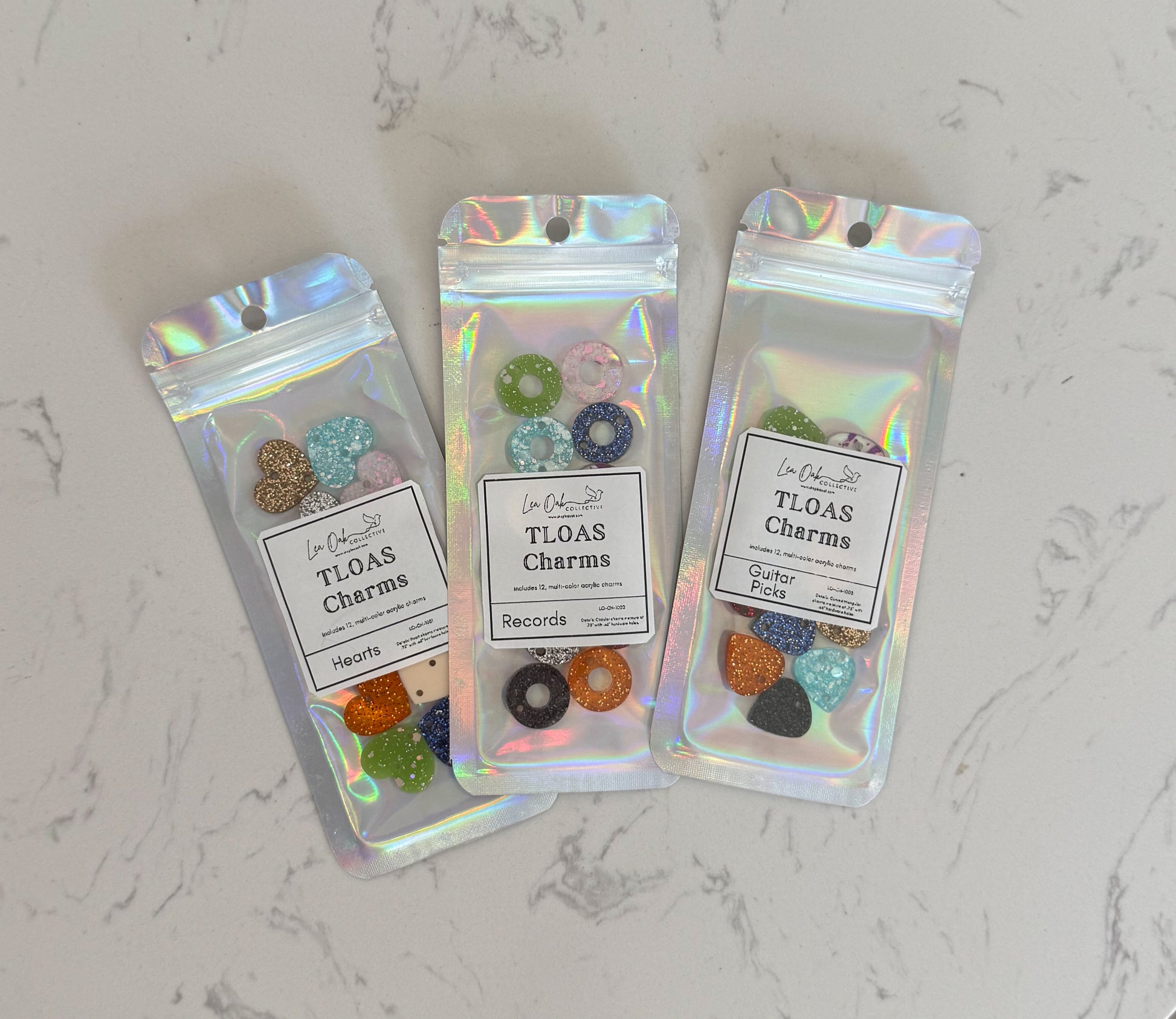 Three packages of TLOAS Charms on a marble surface