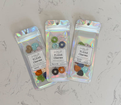 Three packages of TLOAS Charms on a marble surface