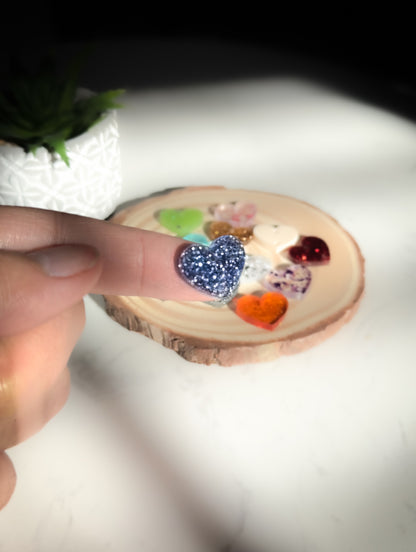 close up of a finger holding a heart-shaped charm.