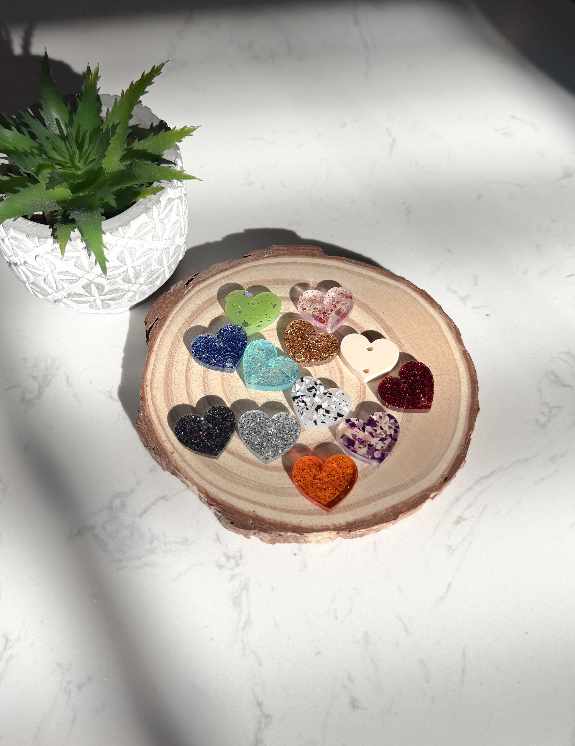 Decorative heart-shaped charms on a wooden slice with a plant in the background