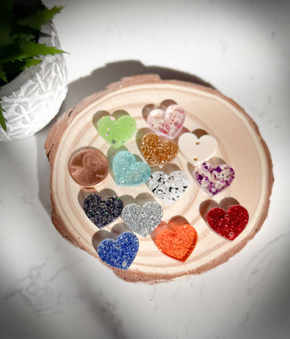 Colorful heart-shaped charms in a wooden holder on a white surface